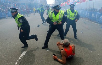Bill Iffrig, 78, lies on the ground as police officers react to a second explosion at the finish line of the Boston Marathon in Boston, Monday, April 15, 2013. Iffrig, of Lake Stevens, Wash., was running his third Boston Marathon and near the finish line when he was knocked down by one of two bomb blasts. (AP Photo/The Boston Globe, John Tlumacki)